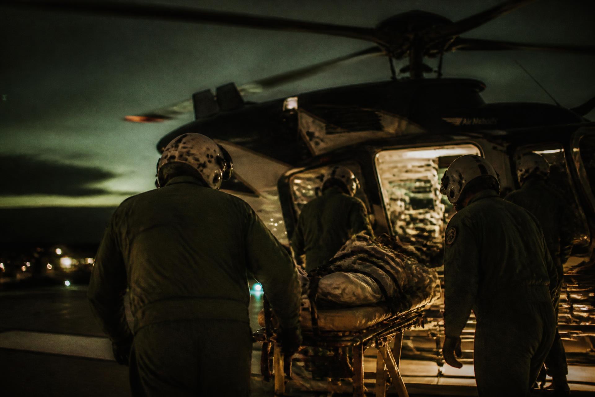 An air medical crew loading a patient onto a helicopter at dusk